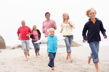 Three generations of a family running along the beach